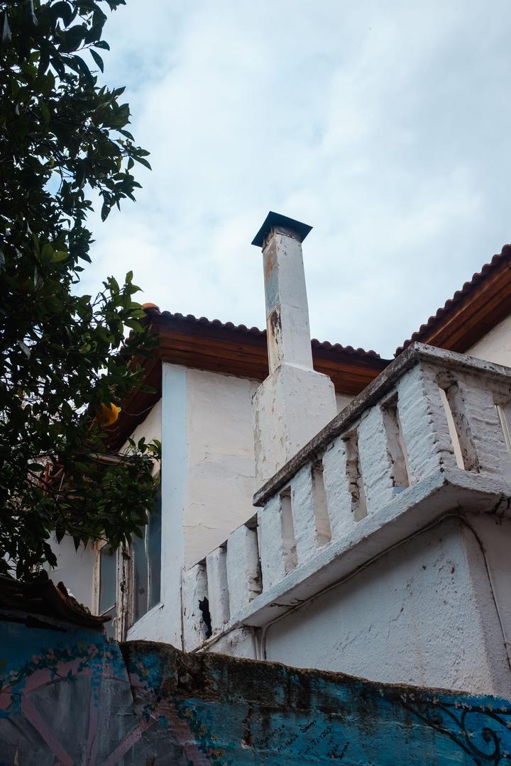 White rendered chimney above a weathered house and tiled roof