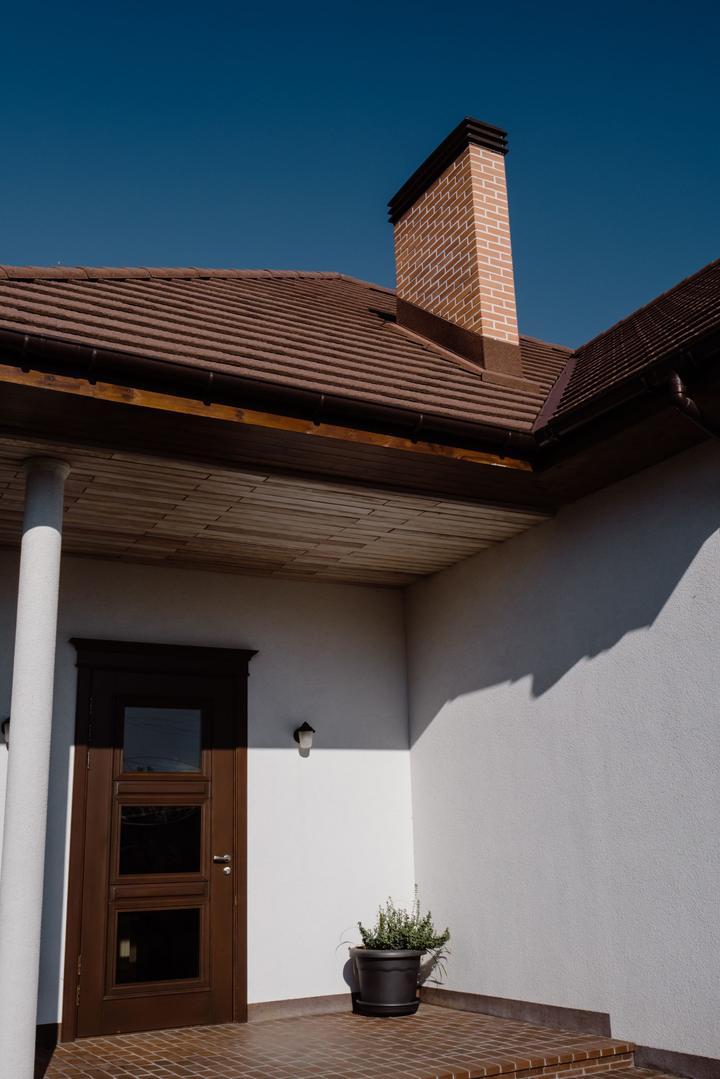 Brick chimney rising above a tiled roof and sheltered entrance